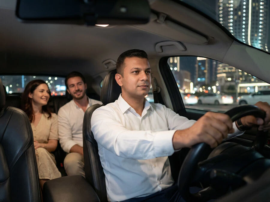 A trusted safe driver in a professional uniform stands next to a car in Dubai, ready for service.